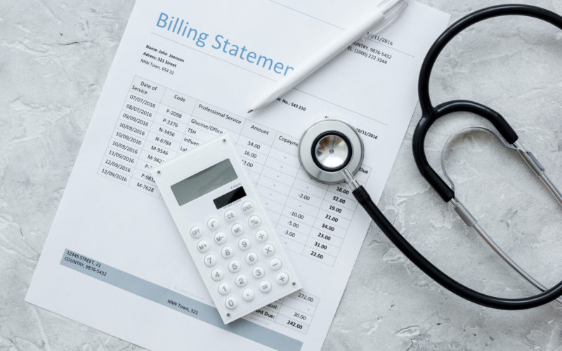 A stethoscope and a medical billing statement on a concrete background.