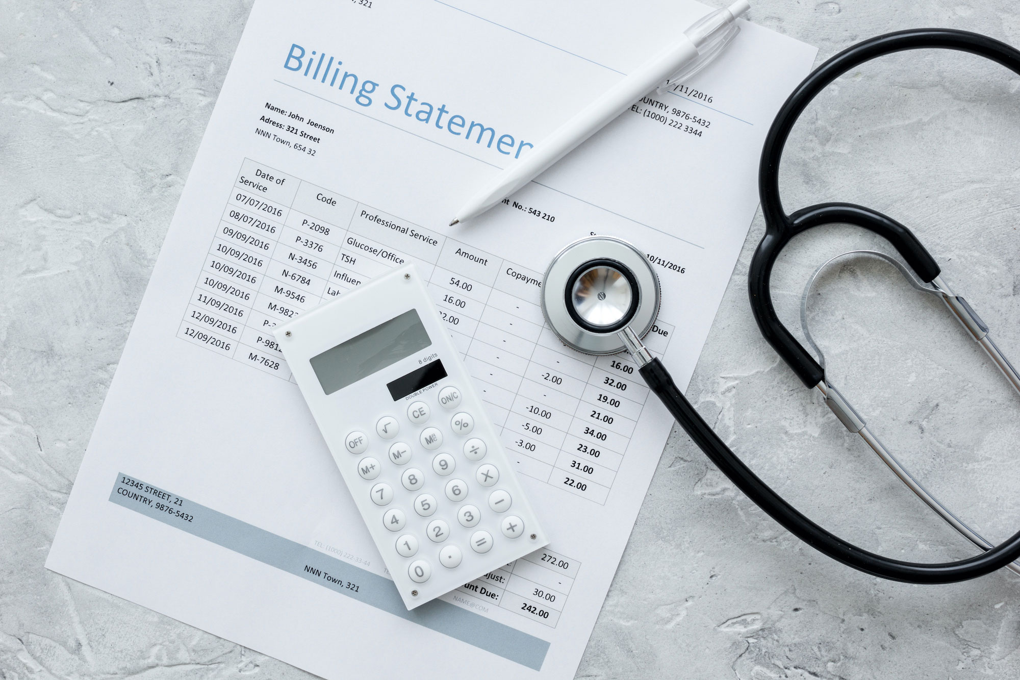 A stethoscope and a medical billing statement on a concrete background.